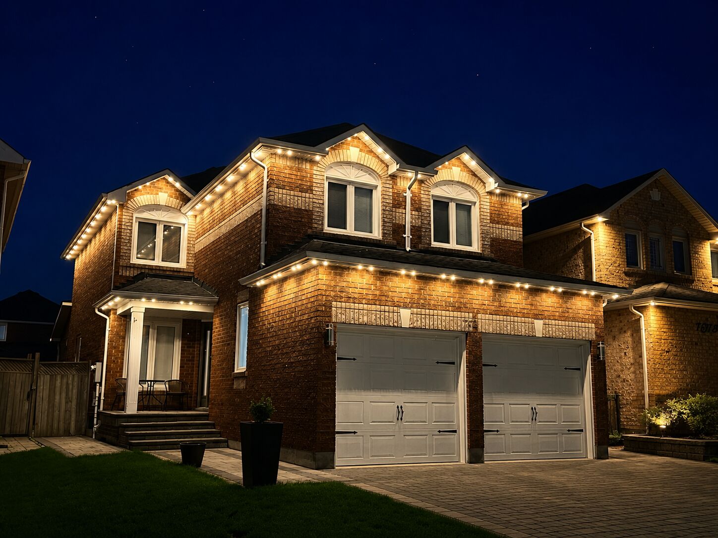Two-storey home glowing with warm white permanent roofline lighting at night